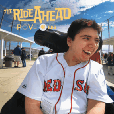 Samuel smiling in his wheelchair wearing a Red Sox jersey at a baseball game. "The Ride Ahead" in yellow text is in the top left corner. Samuel smiling in his wheelchair wearing a Red Sox jersey at a baseball game. "The Ride Ahead" in yellow text is in the top left corner.