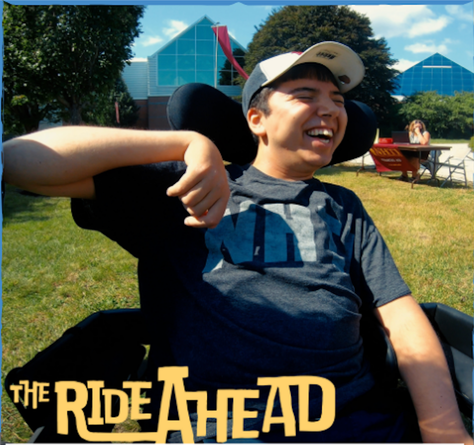 Samuel smiling in his wheelchair wearing